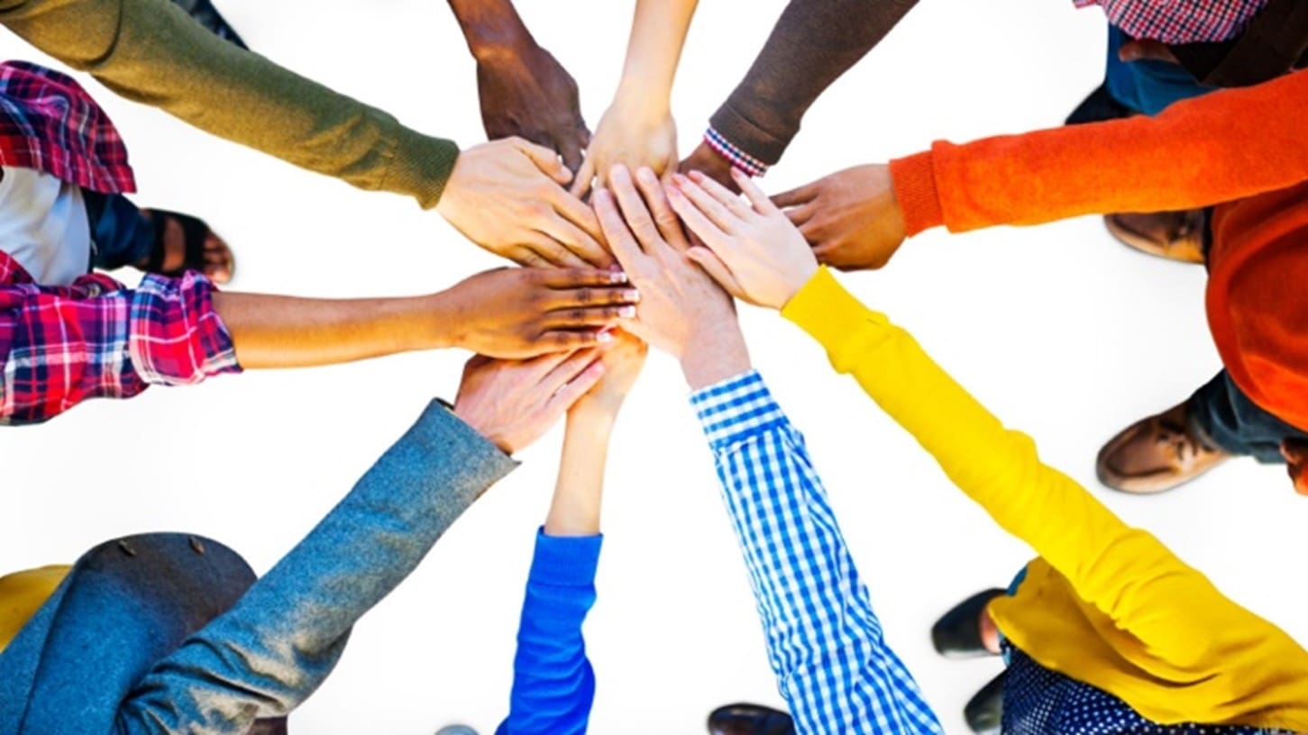 A group of people holding hands in the middle of a circle.