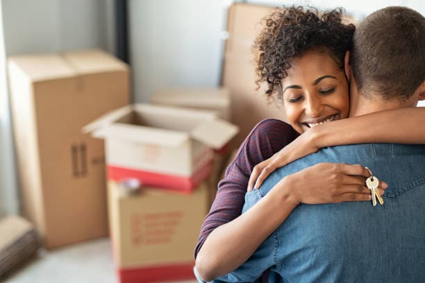 A woman hugging another person in front of boxes.